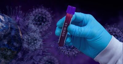 A doctor wearing blue plastic gloves holding a blood sample