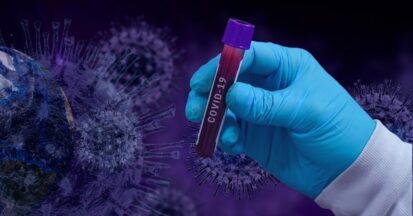 A doctor wearing blue plastic gloves holding a blood sample