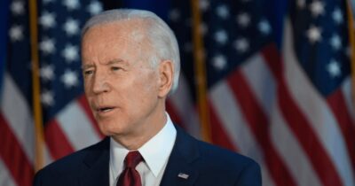 Joe Biden standing in front of the American flag