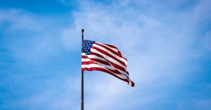 The flag of the United States in the wind against a blue sky