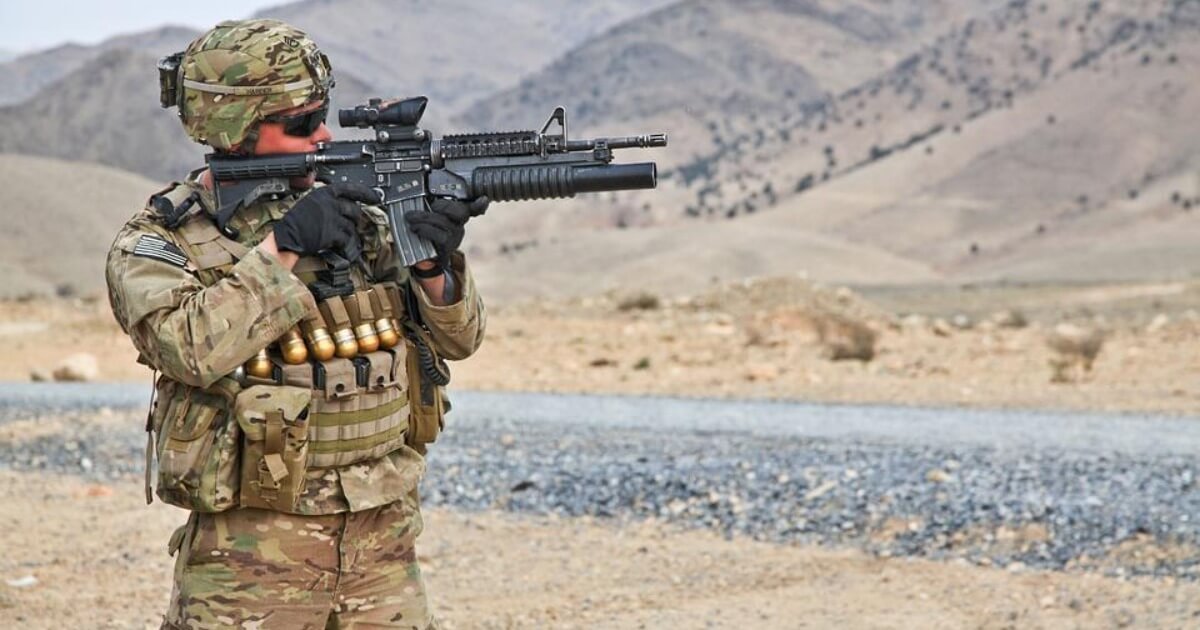 A US soldier aiming his rifle in a valley in Afghanistan
