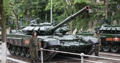 A Russian tank wiht a soldier standing beside it